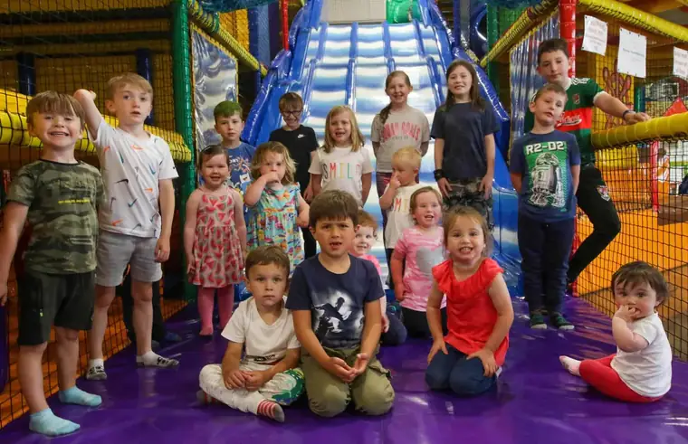 A large group of children gathered at the bottom of the blue slide