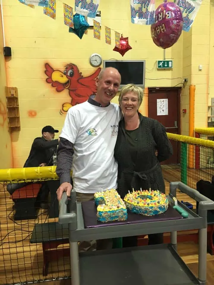 Ray and Barbara, who founded The Pirates Den, smiling behind a birthday cake in the play centre