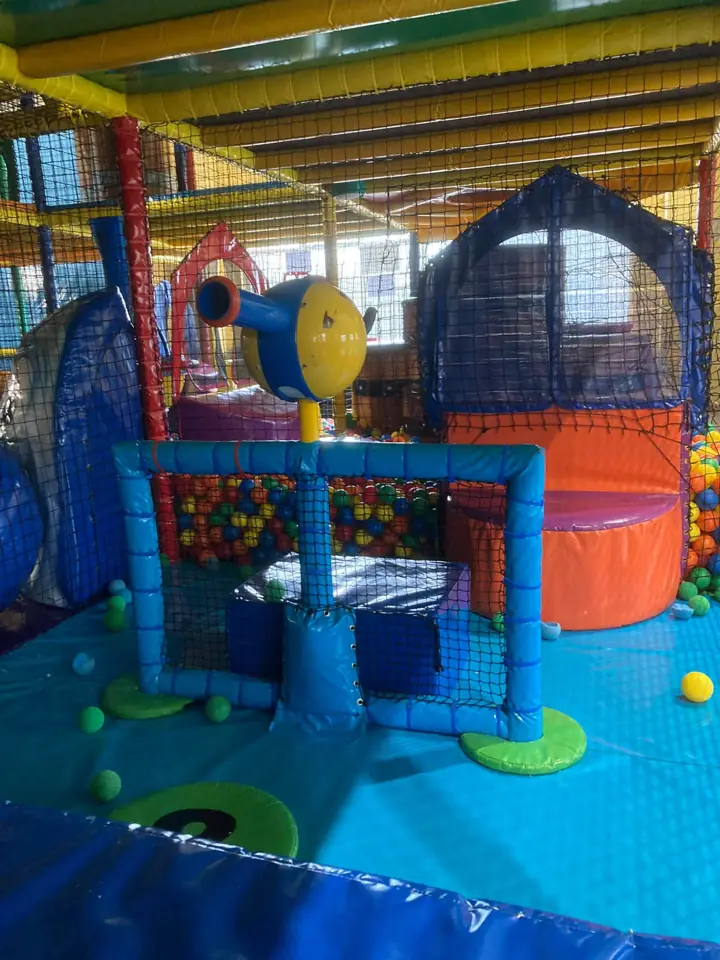 A ball cannon on a netted platform, with the ball pit and soft play blocks behind