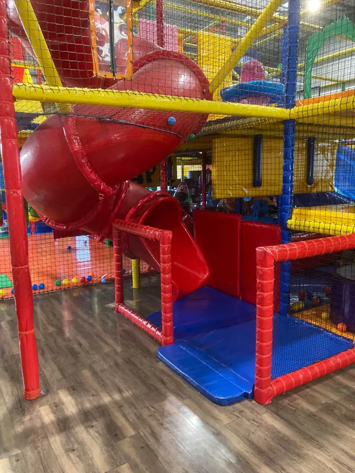 The red tube slide coming down out of the main frame onto a blue landing mat
