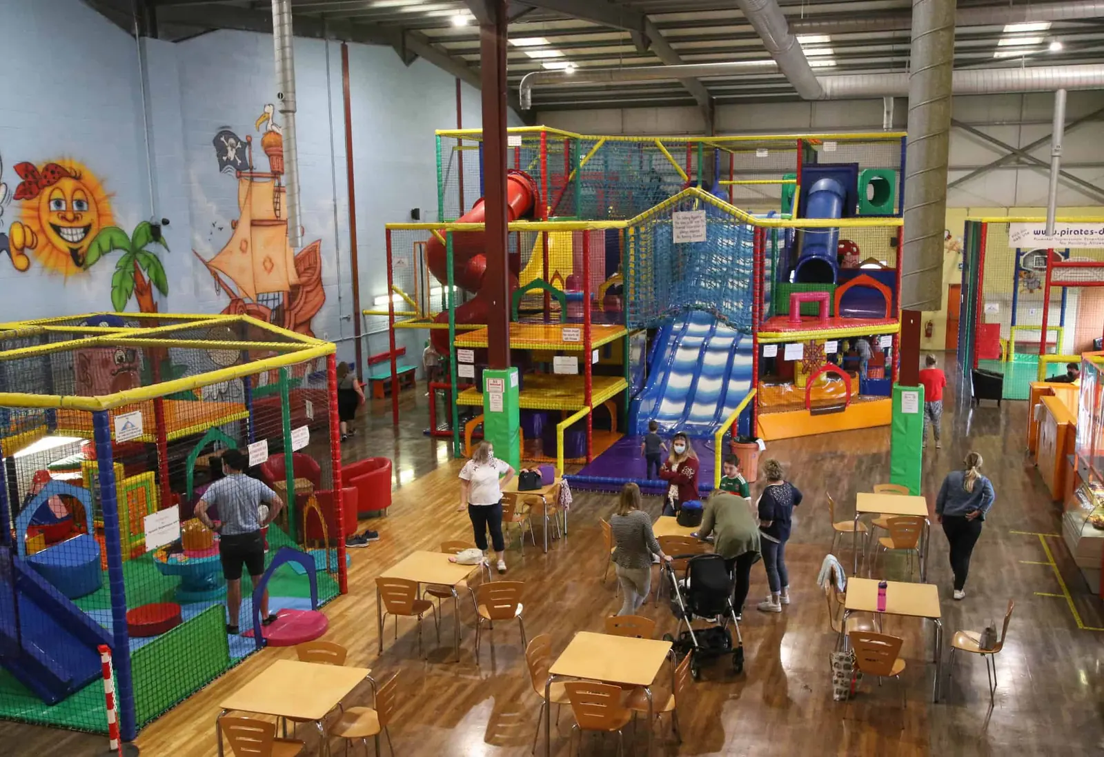 The main play frames and big blue slide seen from above, with families at café tables in front